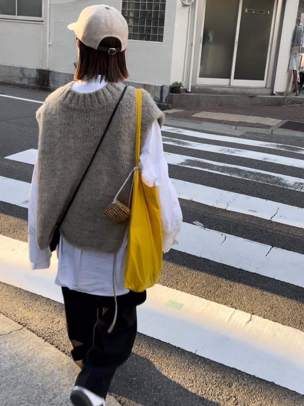 ブラック系のパンツ、ホワイト系のスニーカー、ベージュ系のキャップを着用したレディースの秋コーディネートの4枚目の写真