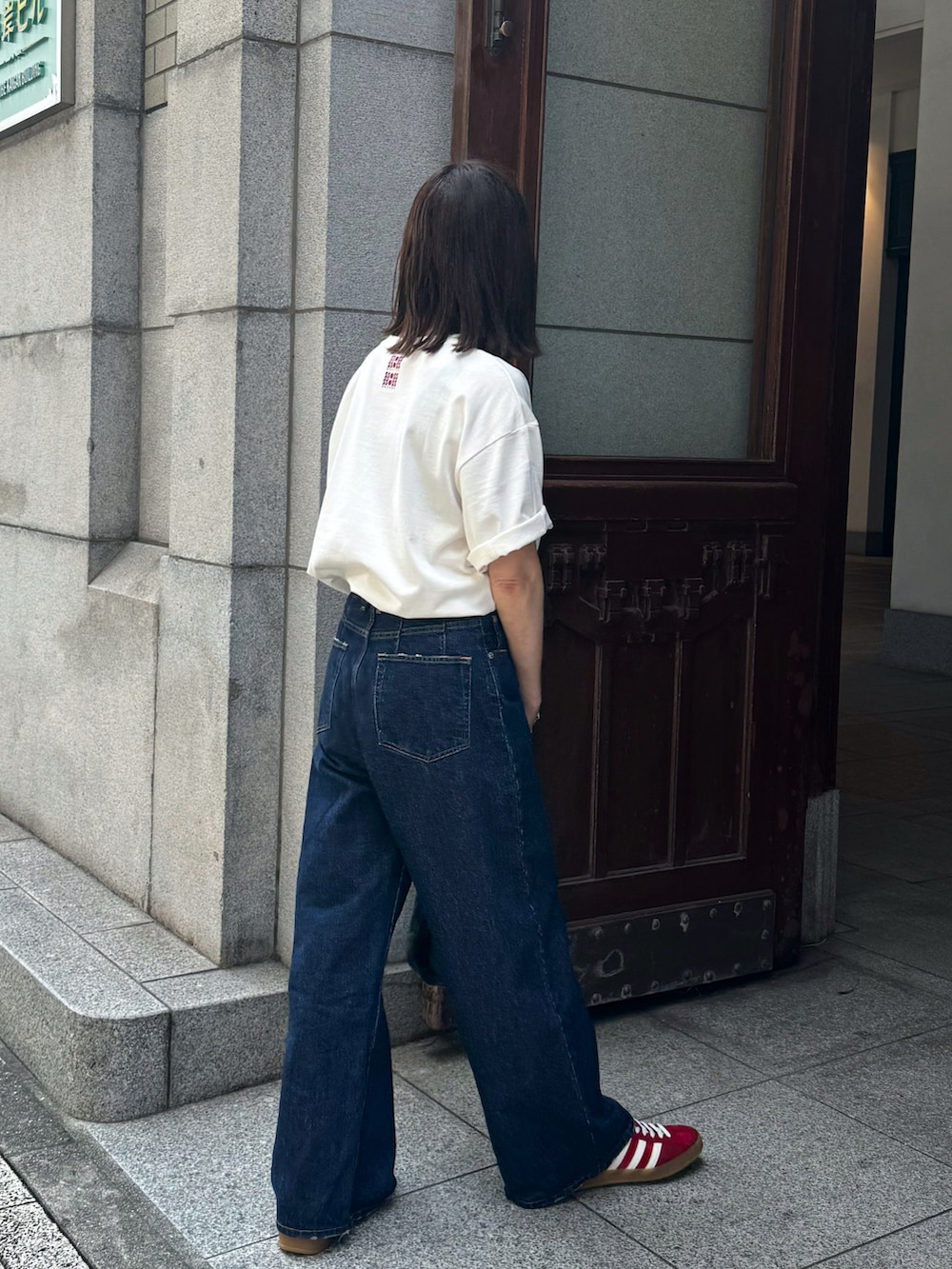 ホワイト系のTシャツ/カットソー、ブルー系のデニムパンツ、レッド系のスニーカーを着用したレディースの夏コーディネートの4枚目の写真