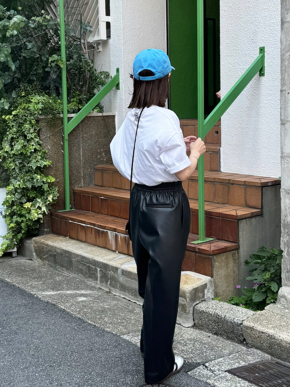 ホワイト系のTシャツ/カットソー、ブラック系のパンツ、ホワイト系のスニーカーを着用したレディースの夏コーディネートの2枚目の写真
