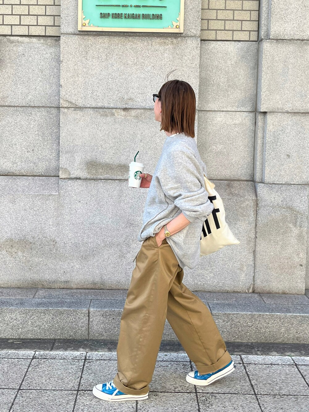 グレー系のスウェット、ベージュ系のチノパンツ、ブラウン系のトートバッグを着用したレディースの秋コーディネートの3枚目の写真