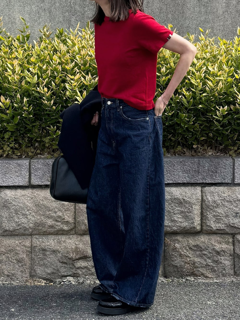 レッド系のニット/セーター、ブルー系のデニムパンツを着用したレディースの春コーディネートの3枚目の写真