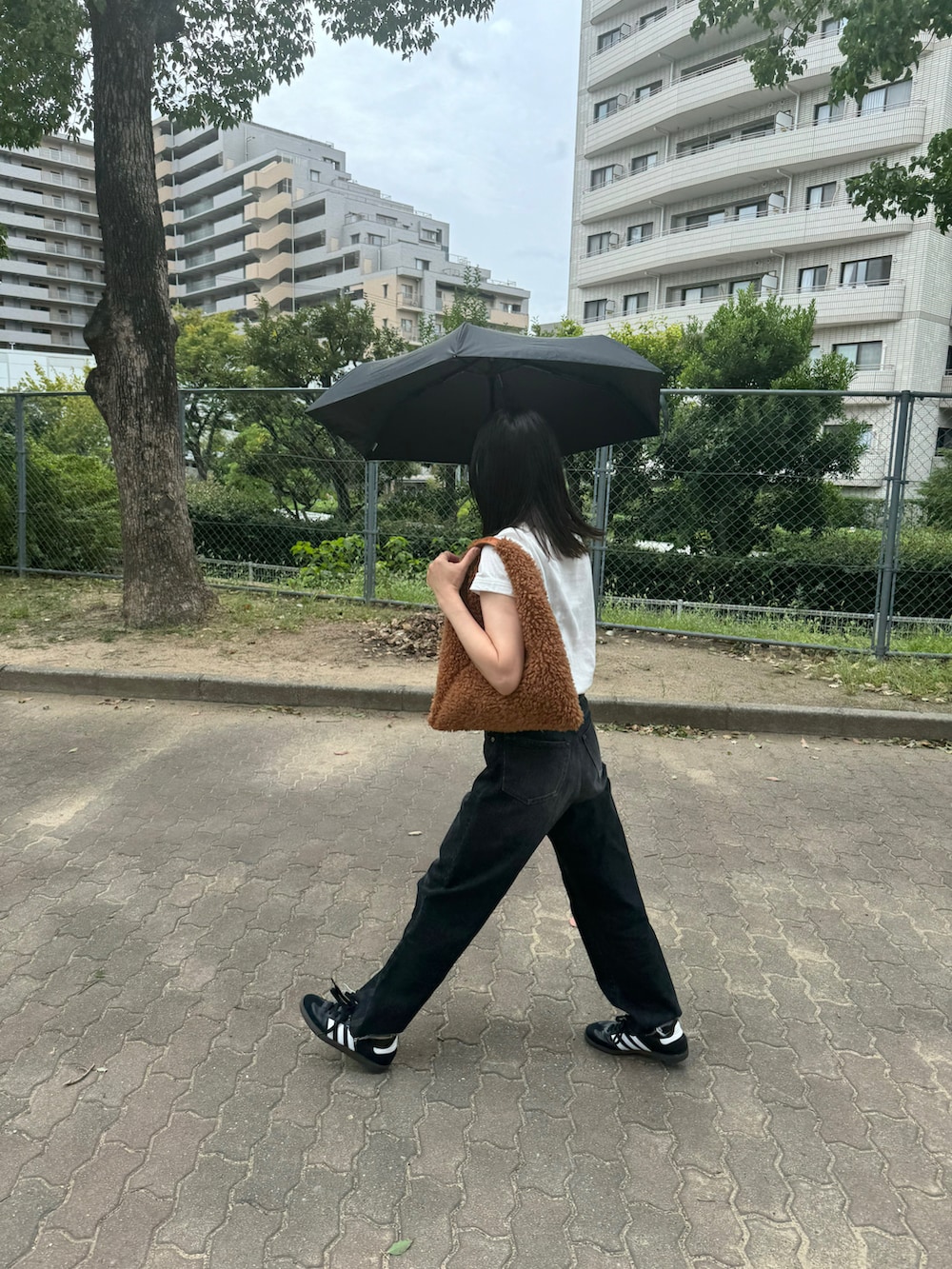 ブラウン系のハンドバッグ、ブラック系のデニムパンツ、ブラック系のスニーカーを着用したレディースの秋コーディネートの2枚目の写真