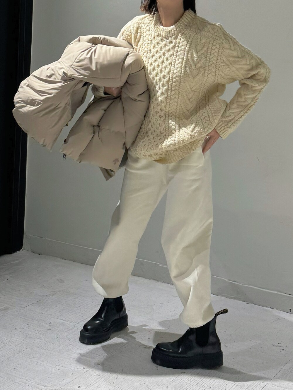 ベージュ系のダウンジャケット/コート、ホワイト系のスウェットパンツ、ブラック系のブーツを着用したレディースの冬コーディネートの2枚目の写真