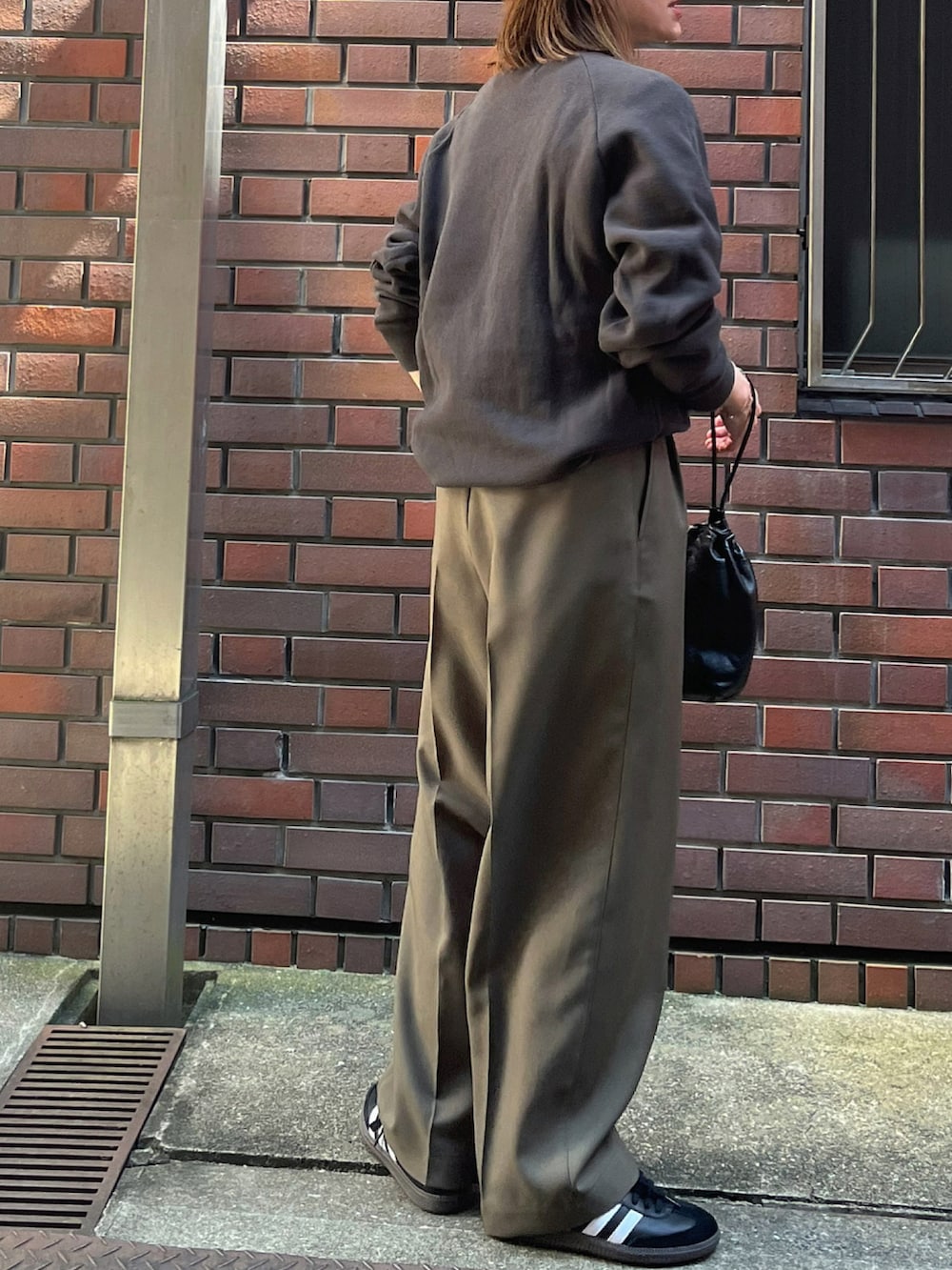 ブラック系のスウェット、グリーン系のパンツ、ブラック系のスニーカーを着用したレディースの夏コーディネートの3枚目の写真