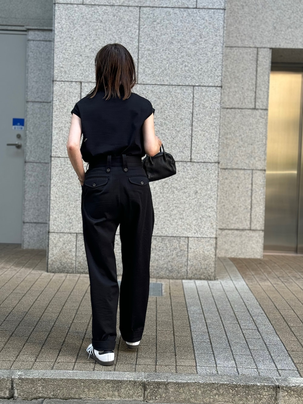 ブラック系のTシャツ/カットソー、ブラック系のチノパンツ、ホワイト系のスニーカーを着用したレディースの夏コーディネートの3枚目の写真