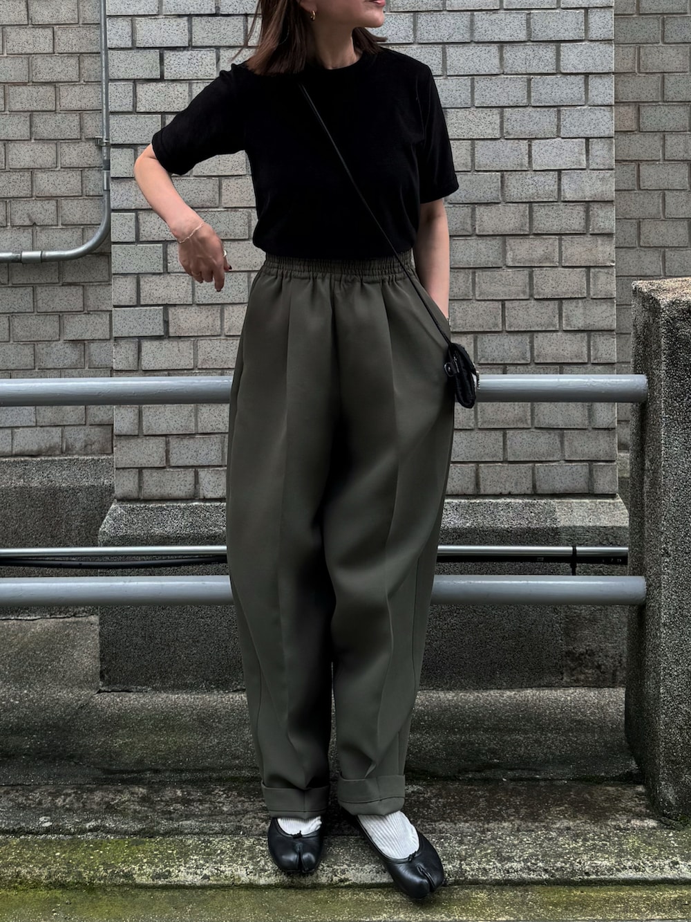 ブラック系のTシャツ/カットソー、グリーン系のパンツ、ブラック系のバレエシューズを着用したレディースの夏コーディネートの5枚目の写真