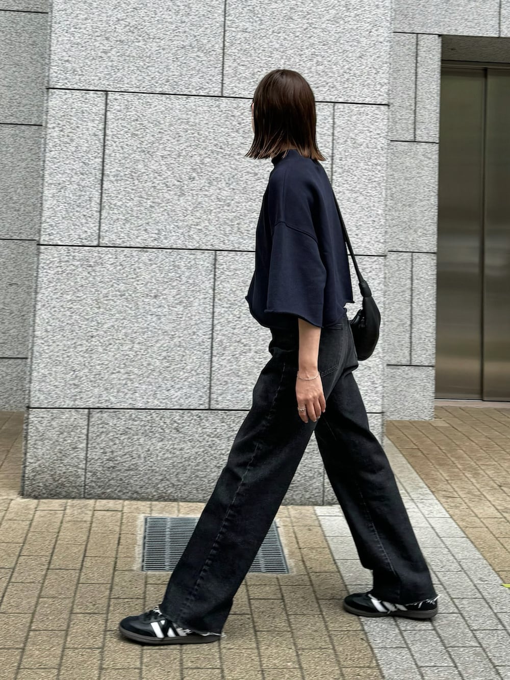 ブラック系のデニムパンツ、ブラック系のTシャツ/カットソー、ブラック系のスニーカーを着用したレディースの春コーディネートの3枚目の写真