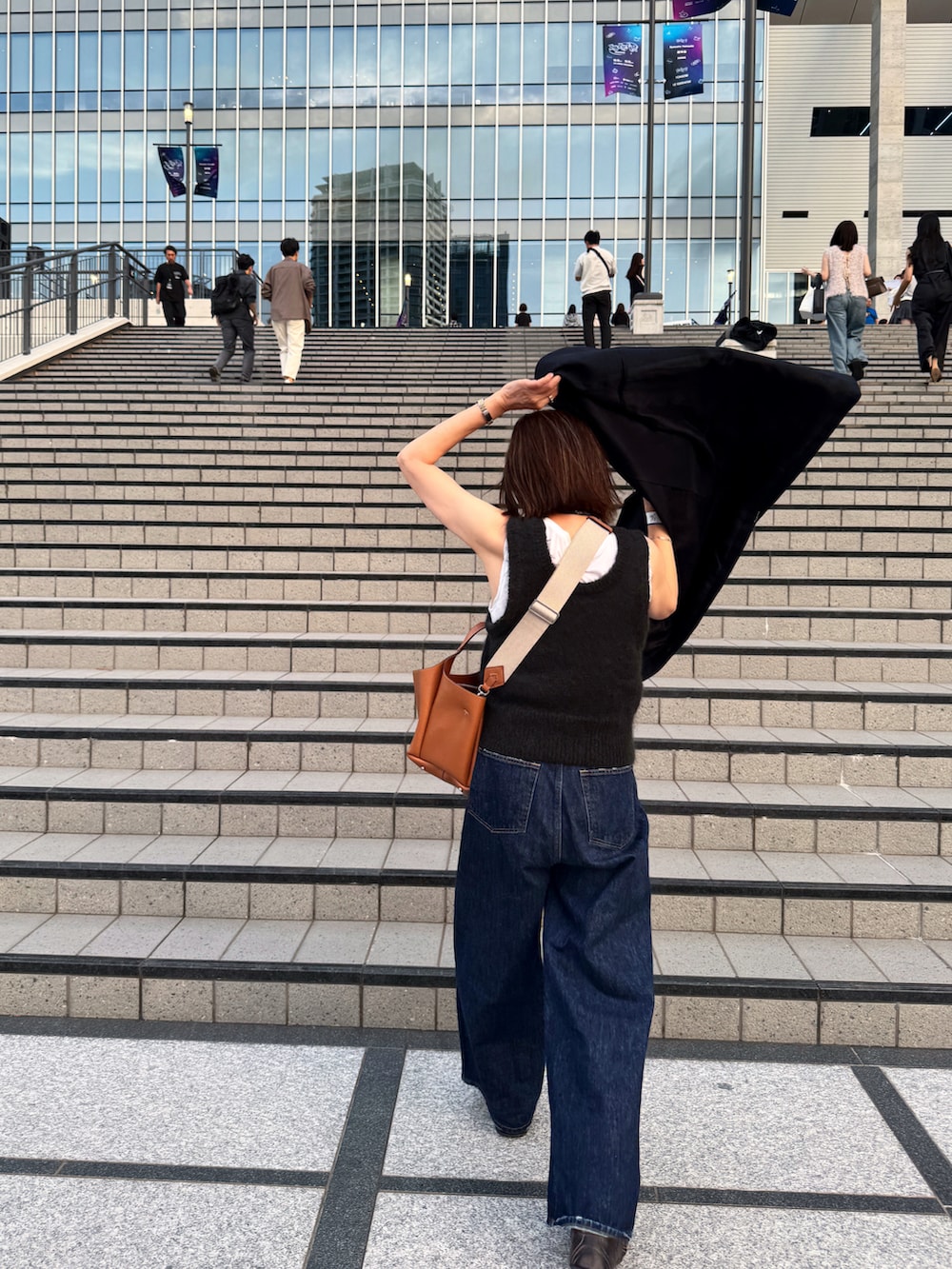 ブルー系のデニムパンツ、ホワイト系のタンクトップ、ブラック系のスニーカーを着用したレディースの秋コーディネートの3枚目の写真