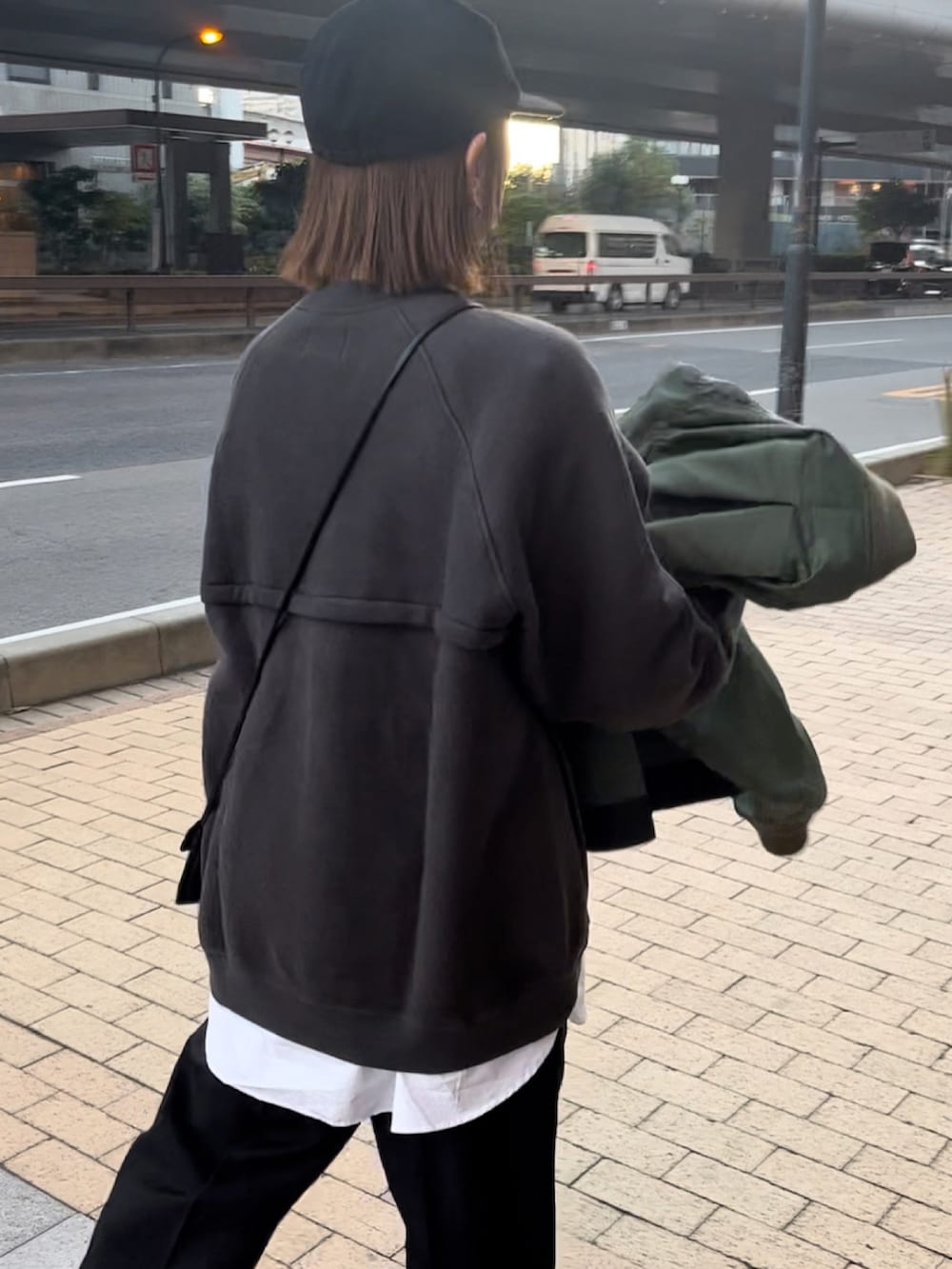 グリーン系のスウェット、ブラック系のパンツ、ブラック系のスニーカーを着用したレディースの秋コーディネートの3枚目の写真