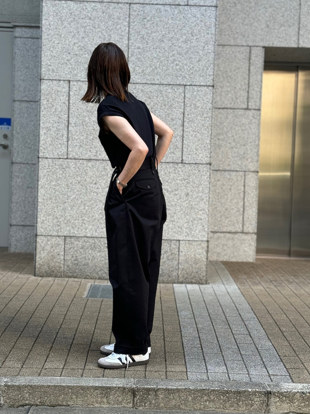 ブラック系のTシャツ/カットソー、ブラック系のチノパンツ、ホワイト系のスニーカーを着用したレディースの夏コーディネートの2枚目の写真