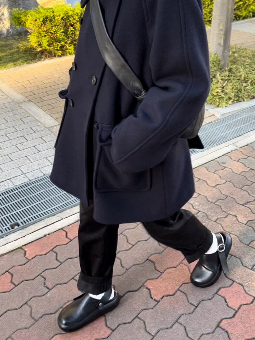 ブルー系のピーコート、ブラック系のパンツ、ブラック系のショルダーバッグを着用したレディースの秋コーディネートの2枚目の写真