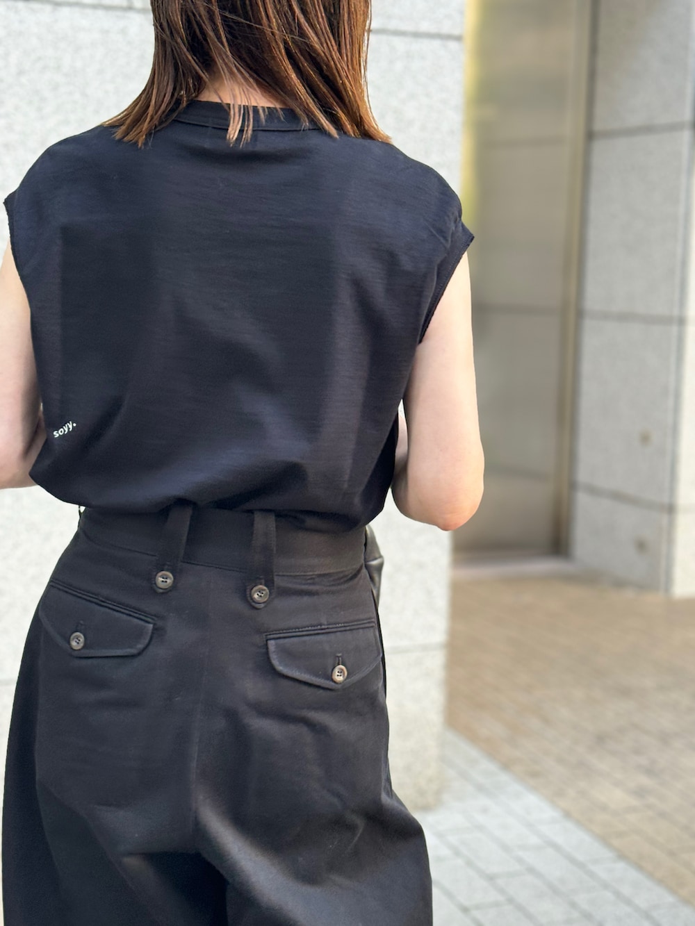 ブラック系のTシャツ/カットソー、ブラック系のチノパンツ、ホワイト系のスニーカーを着用したレディースの夏コーディネートの4枚目の写真