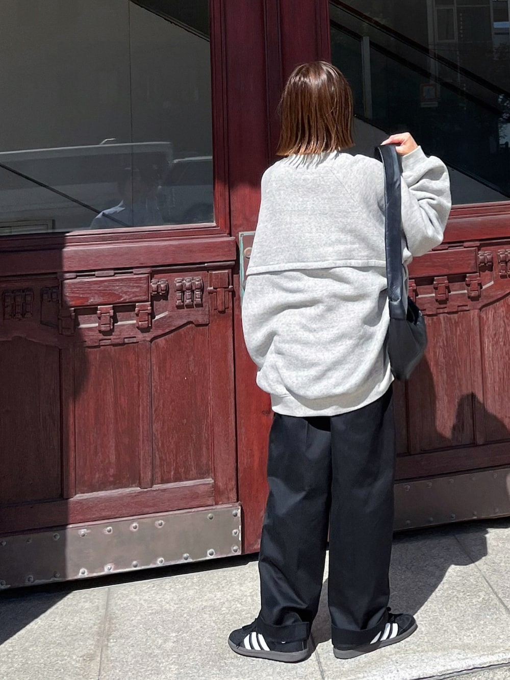 グレー系のスウェット、ブラック系のチノパンツ、ブラック系のスニーカーを着用したレディースの秋コーディネートの3枚目の写真