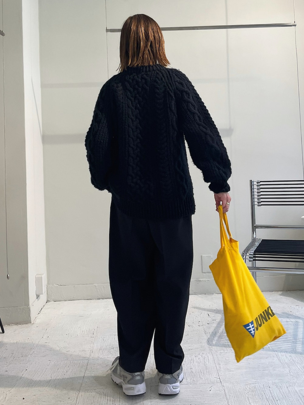 ブラック系のニット/セーター、ブラック系のパンツ、グレー系のスニーカーを着用したレディースの秋コーディネートの4枚目の写真