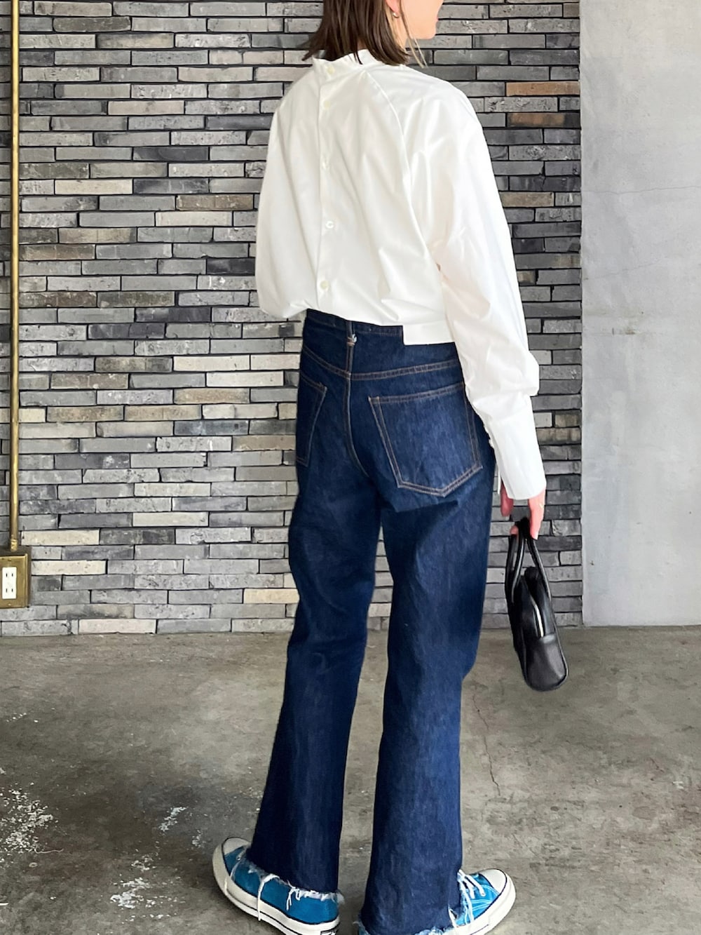 ホワイト系のシャツ/ブラウス、ブラック系のボストンバッグ、ブルー系のデニムパンツを着用したレディースの春コーディネートの2枚目の写真