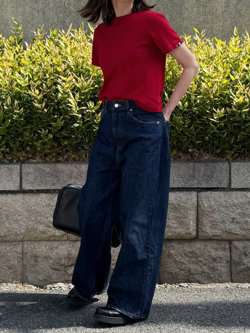 レッド系のニット/セーター、ブルー系のデニムパンツを着用したレディースの春コーディネートの2枚目の写真