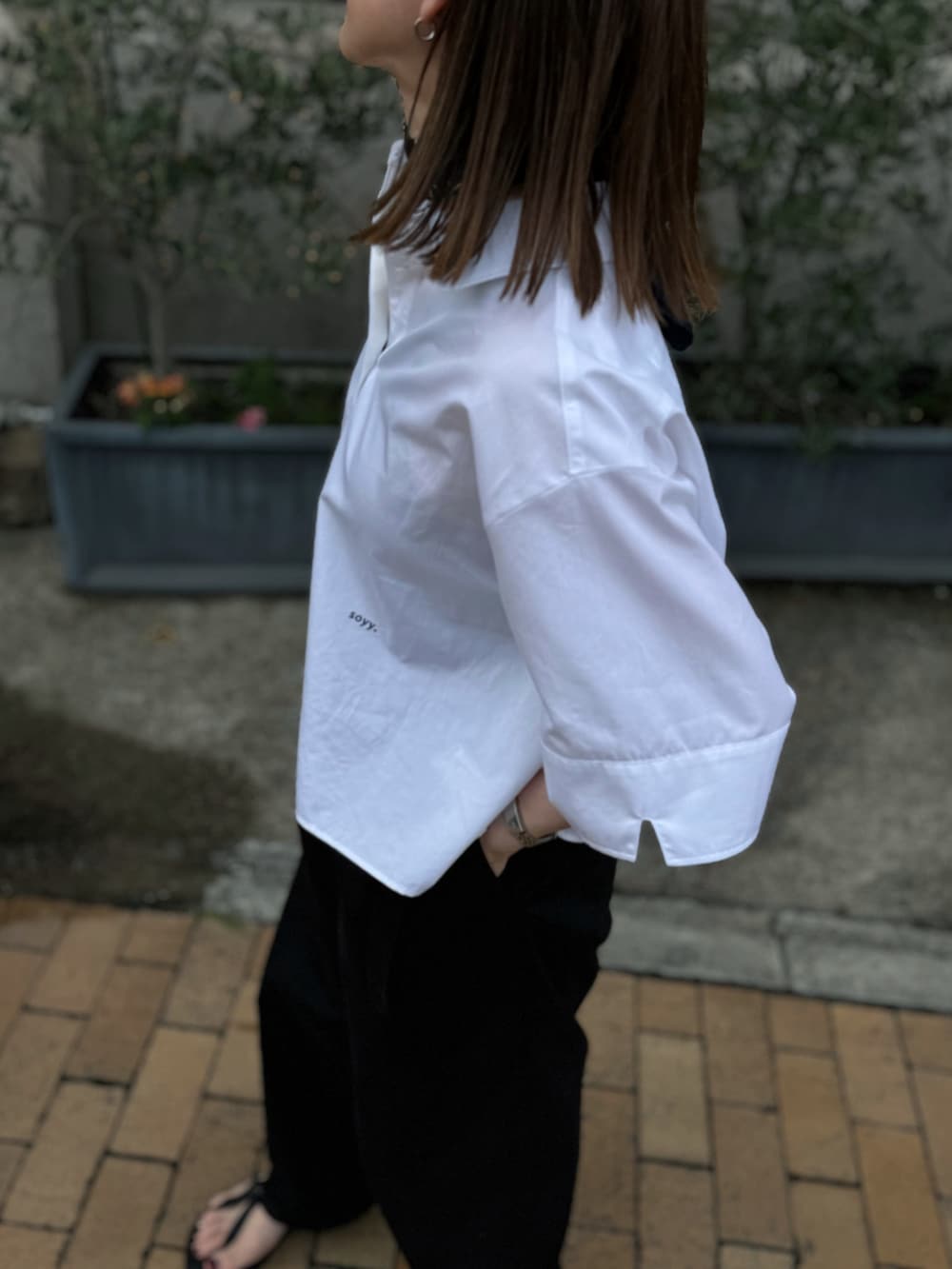 ホワイト系のシャツ/ブラウス、ブラック系のチノパンツ、シルバー系のブレスレットを着用したレディースの夏コーディネートの3枚目の写真