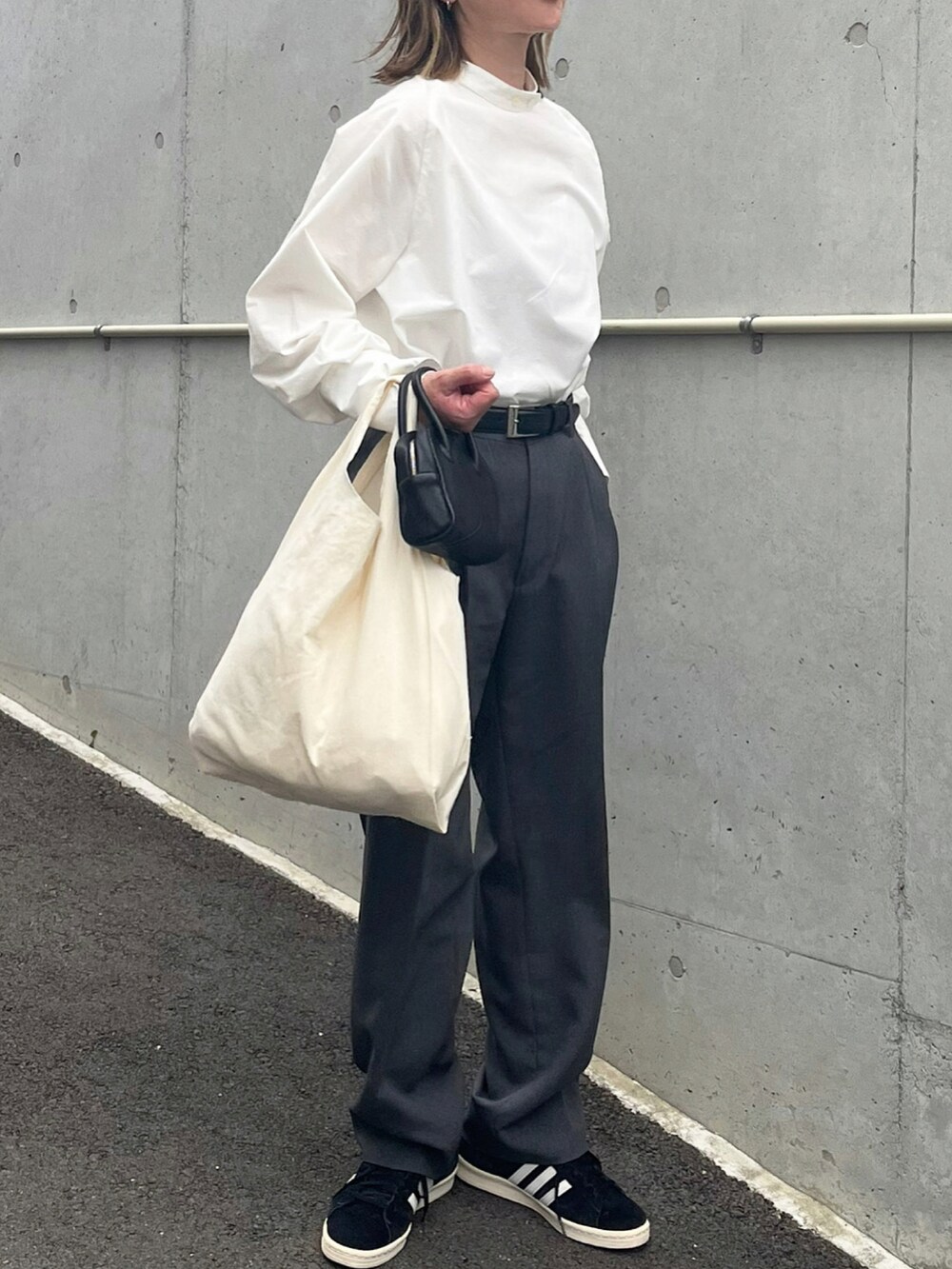 ホワイト系のシャツ/ブラウス、グレー系のスラックス、ブラック系のスニーカーを着用したレディースの春コーディネートの2枚目の写真