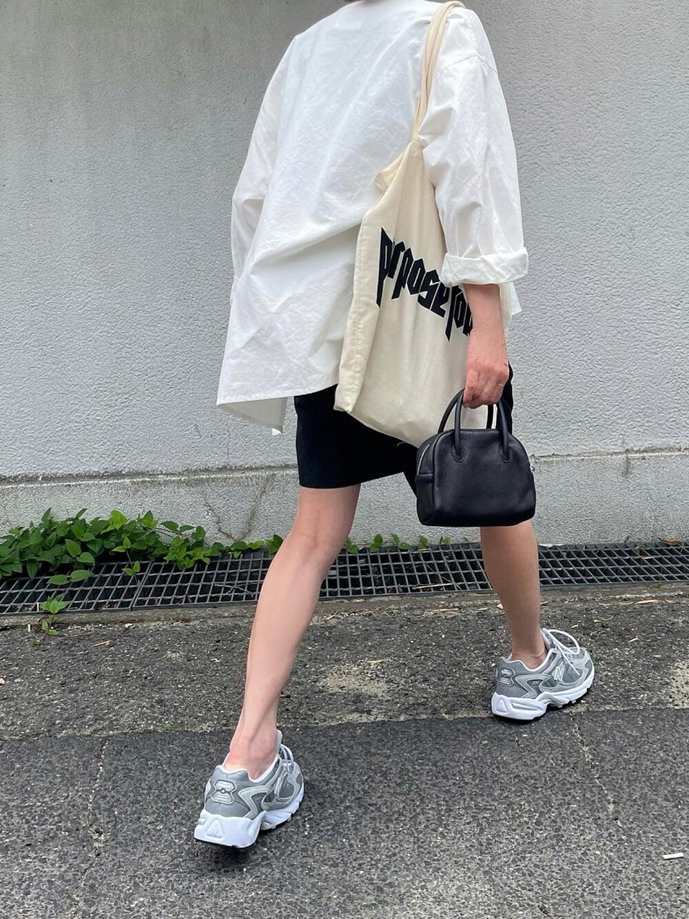 ブラック系のタンクトップ、ブラック系のボストンバッグ、グレー系のスニーカーを着用したレディースの夏コーディネートの3枚目の写真