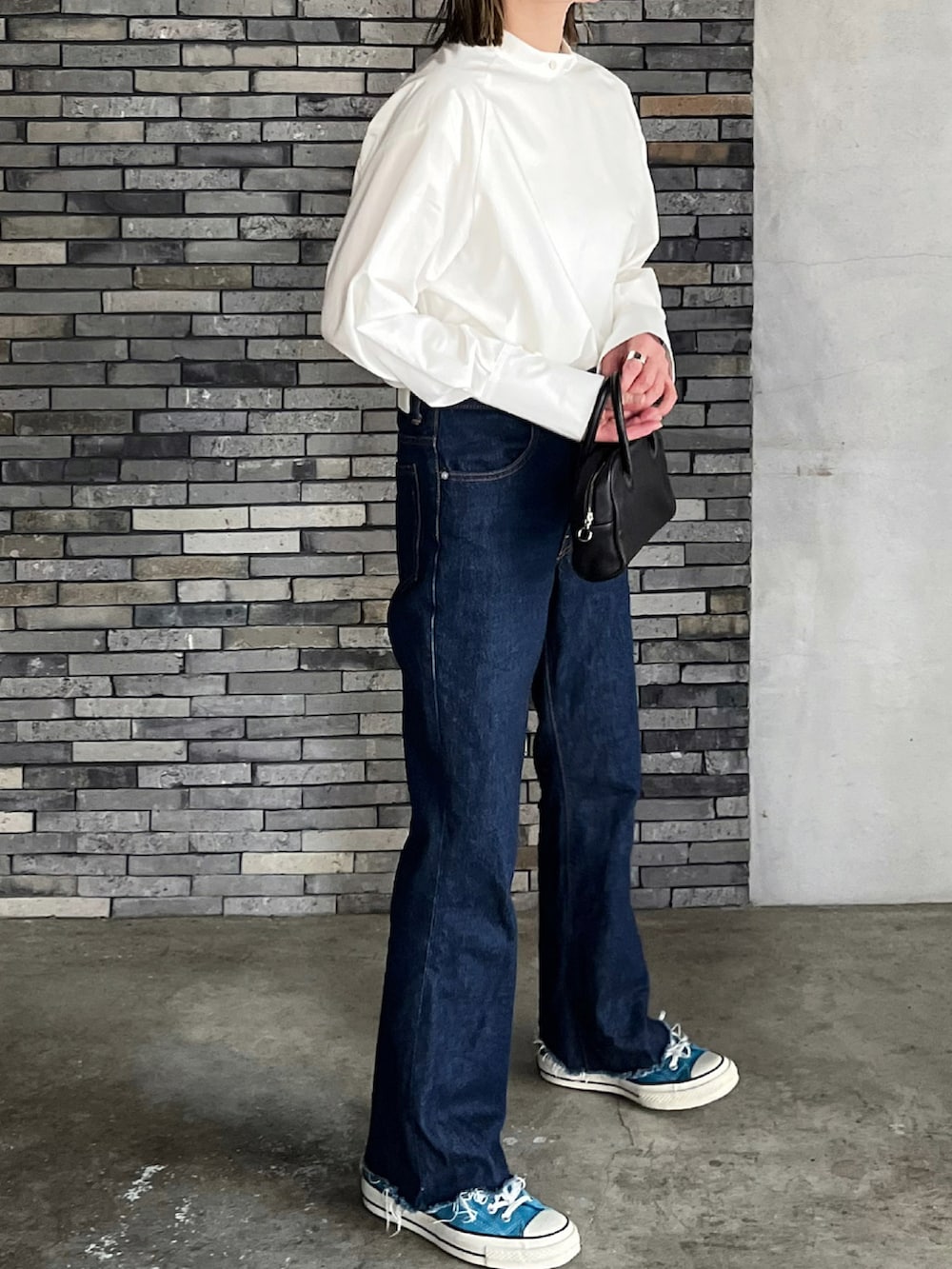 ホワイト系のシャツ/ブラウス、ブラック系のボストンバッグ、ブルー系のデニムパンツを着用したレディースの春コーディネートの3枚目の写真