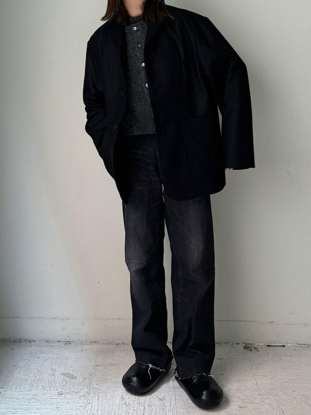 ブラック系のテーラードジャケット、ブラック系のスラックス、グレー系のカーディガン/ボレロを着用したレディースの秋コーディネートの3枚目の写真