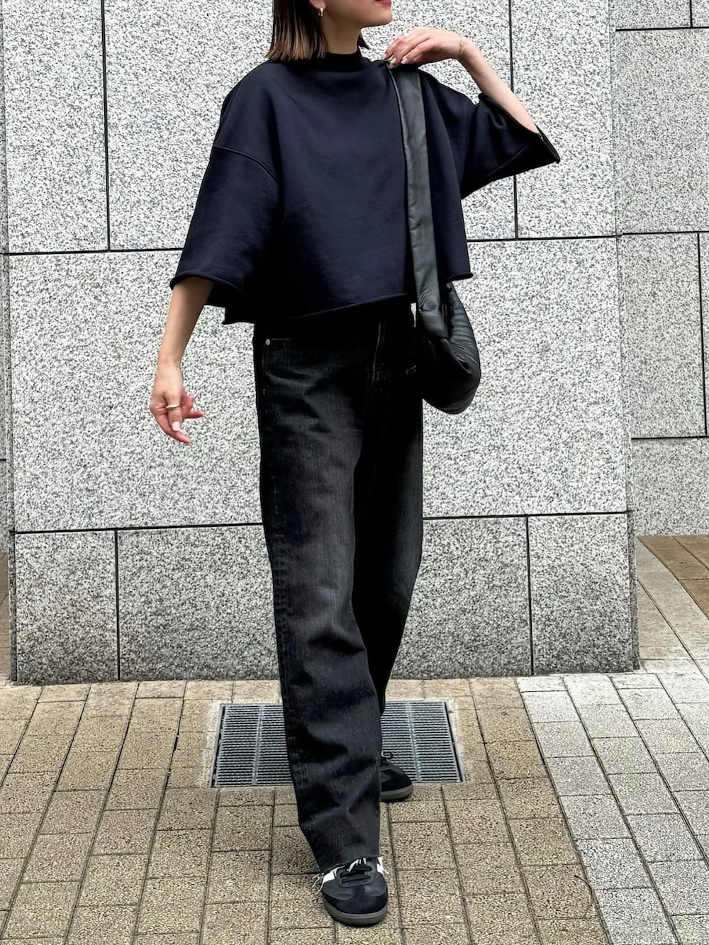 ブラック系のデニムパンツ、ブラック系のTシャツ/カットソー、ブラック系のスニーカーを着用したレディースの春コーディネートの2枚目の写真