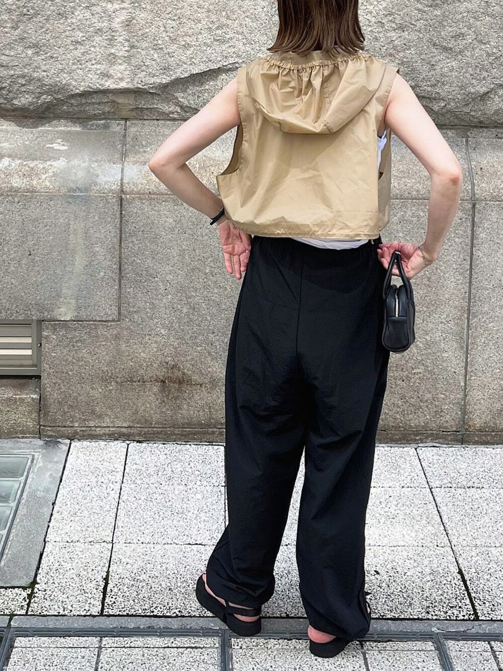 ホワイト系のタンクトップ、ブラック系のパンツ、シルバー系のブレスレットを着用したレディースの夏コーディネートの4枚目の写真