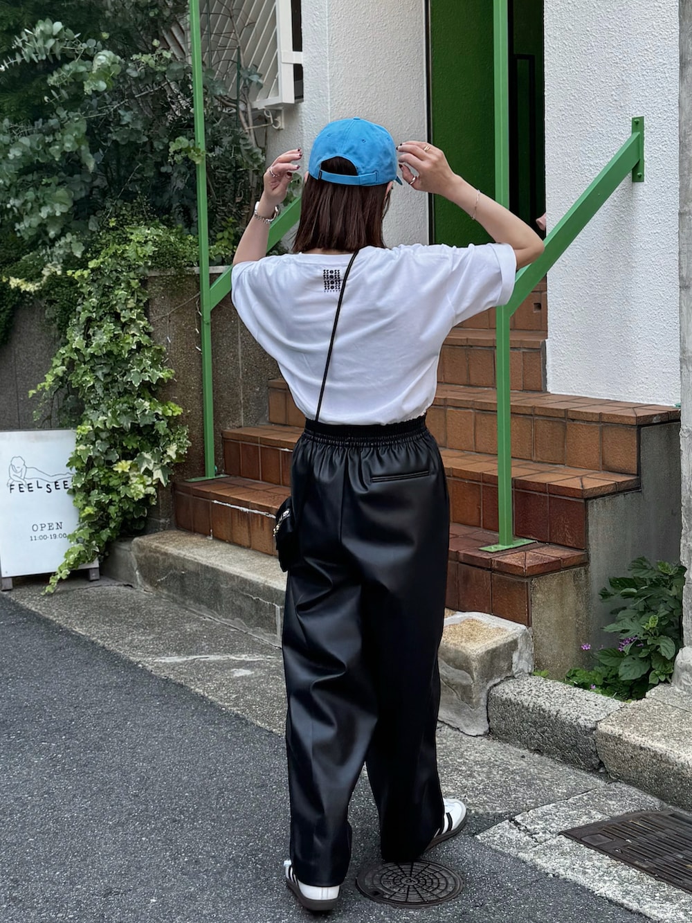 ホワイト系のTシャツ/カットソー、ブラック系のパンツ、ホワイト系のスニーカーを着用したレディースの夏コーディネートの3枚目の写真