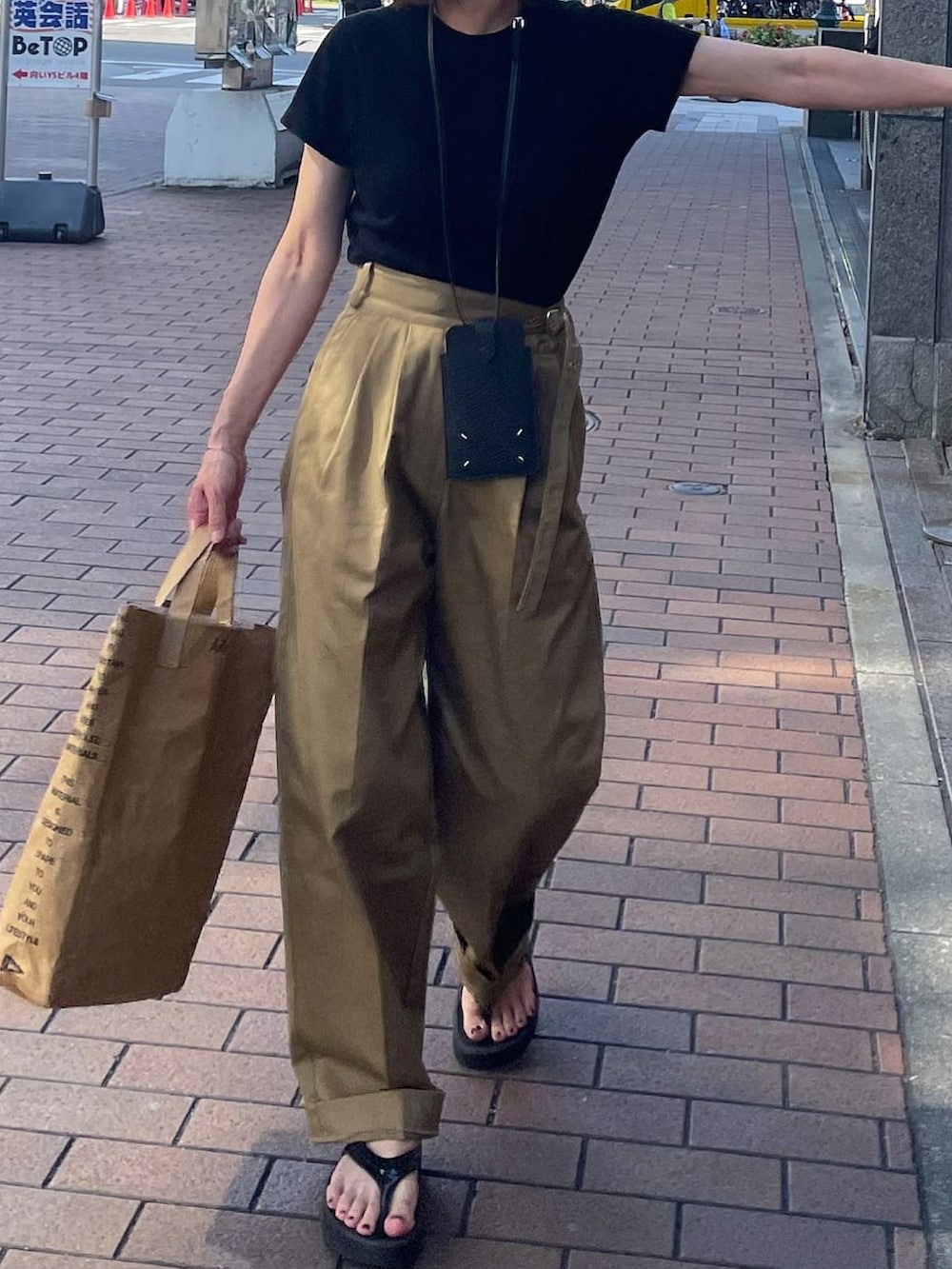 ベージュ系のチノパンツ、ブラック系のサンダル、シルバー系のブレスレットを着用したレディースの夏コーディネートの4枚目の写真