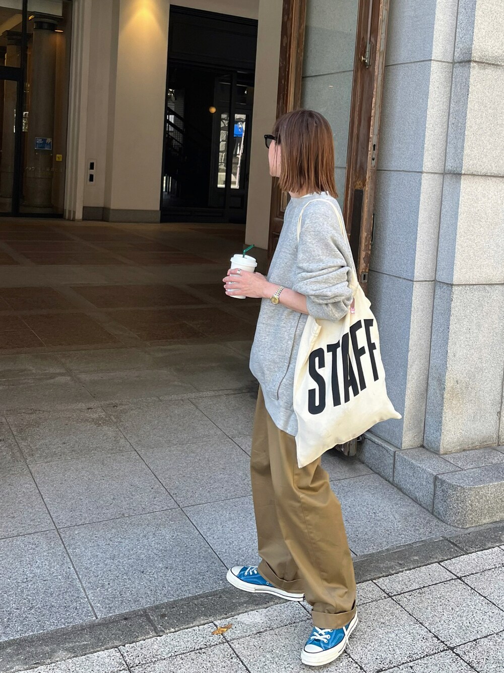 グレー系のスウェット、ベージュ系のチノパンツ、ブラウン系のトートバッグを着用したレディースの秋コーディネートの2枚目の写真