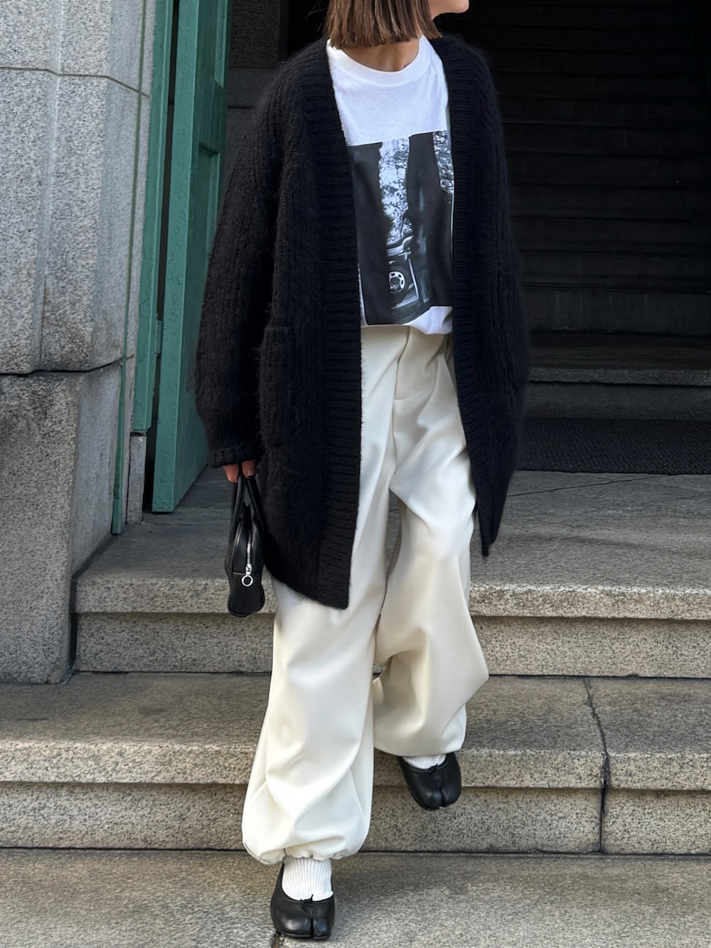 ブラック系のパンツ、ブラック系のバレエシューズ、ゴールド系のピアス（両耳用）を着用したレディースの秋コーディネートの2枚目の写真