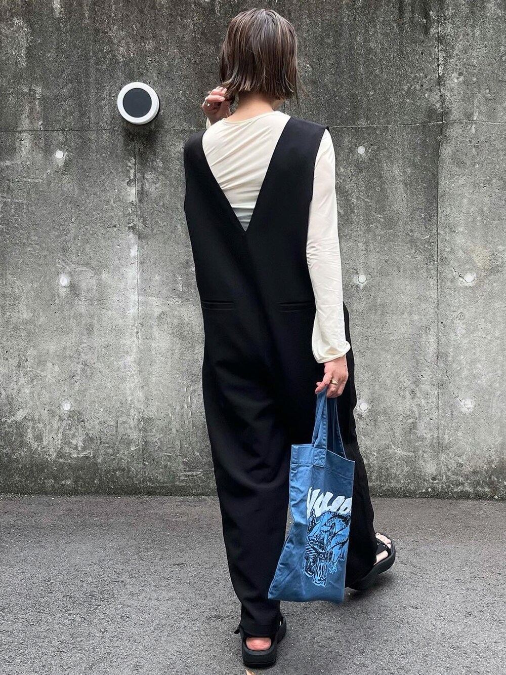 ブルー系のトートバッグ、ブラック系のサンダルを着用したレディースの春コーディネートの3枚目の写真