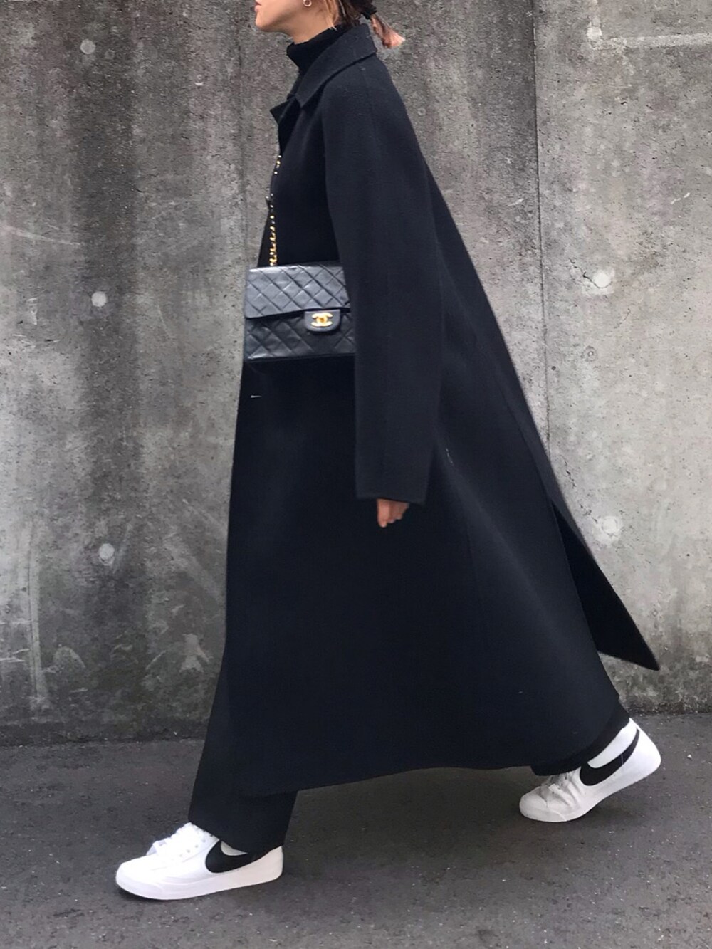 ブラック系のステンカラーコート、シルバー系のピアス（両耳用）を着用したレディースの冬コーディネートの3枚目の写真