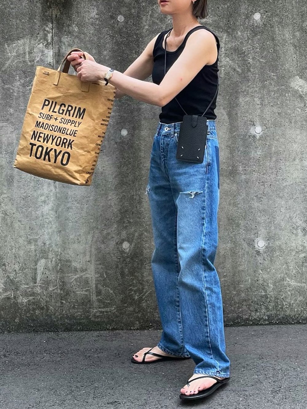 ブラック系のタンクトップ、ブルー系のデニムパンツ、ブラック系のスマホケース/カバーを着用したレディースの夏コーディネートの2枚目の写真