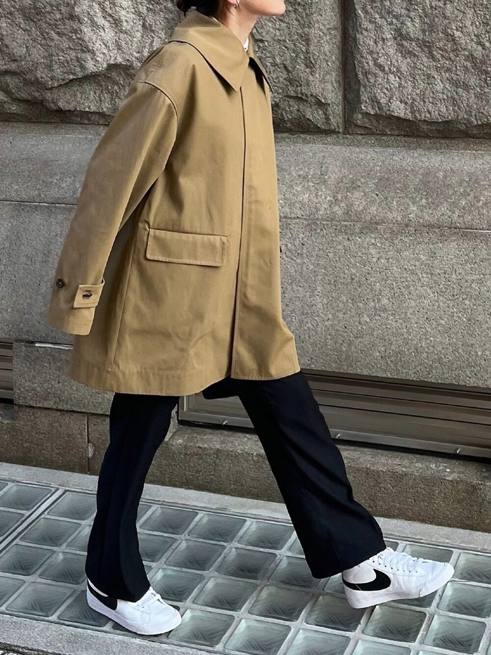 ブラウン系のステンカラーコート、ブラック系のニット/セーターを着用したレディースの冬コーディネートの2枚目の写真