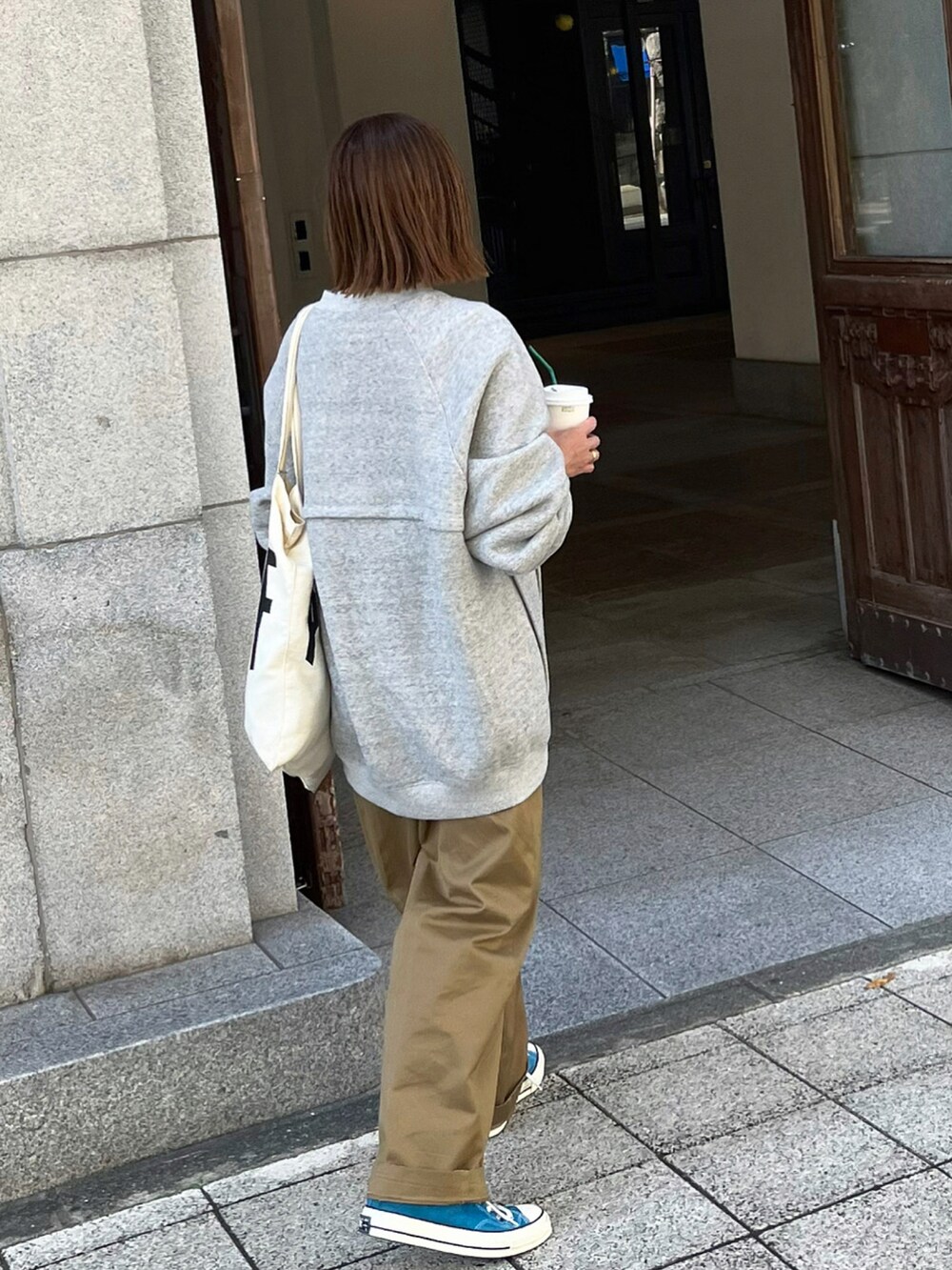 グレー系のスウェット、ベージュ系のチノパンツ、ブラウン系のトートバッグを着用したレディースの秋コーディネートの5枚目の写真
