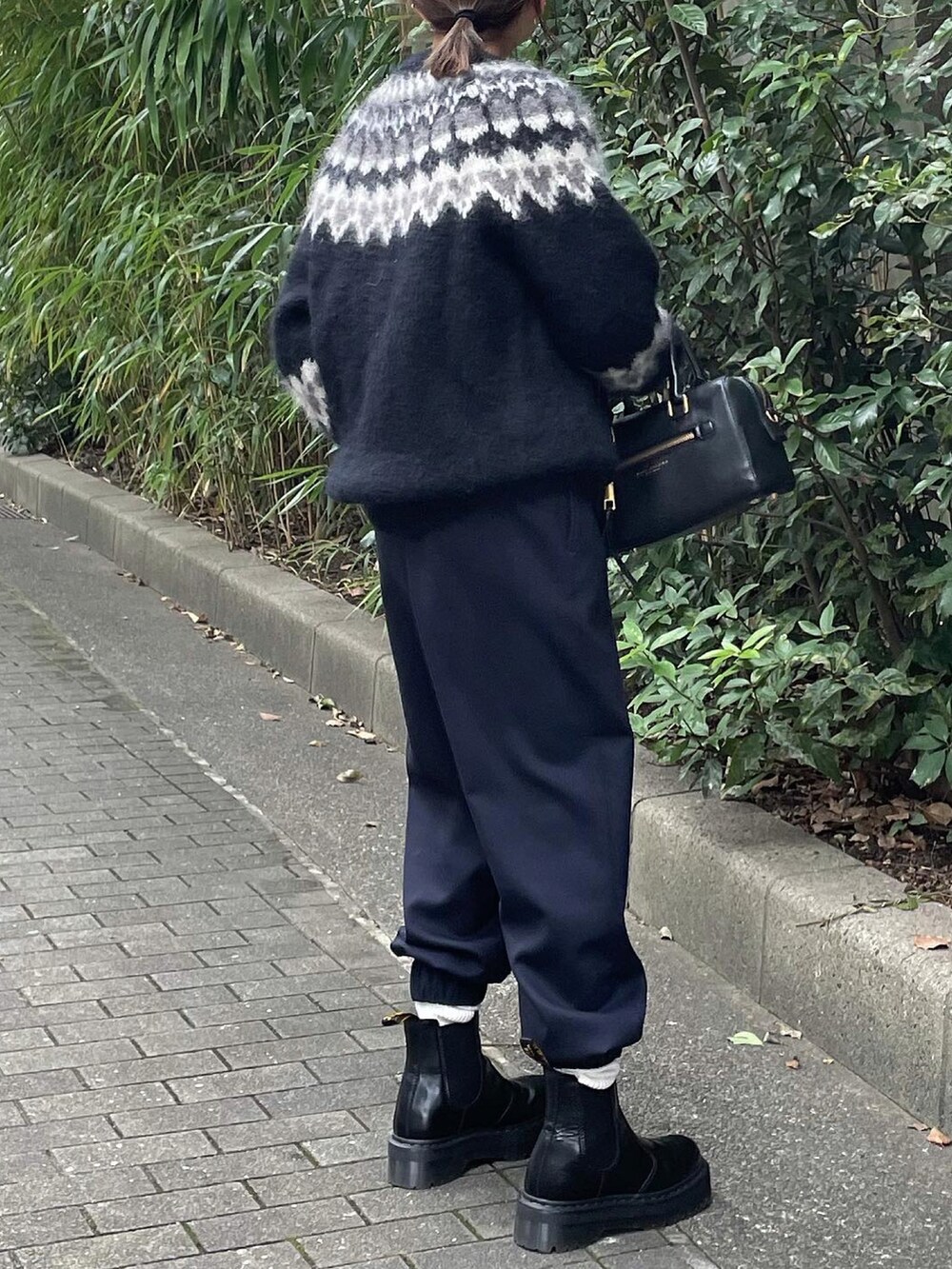 ブラック系のニット/セーター、ブルー系のスラックスを着用したレディースの秋コーディネートの4枚目の写真