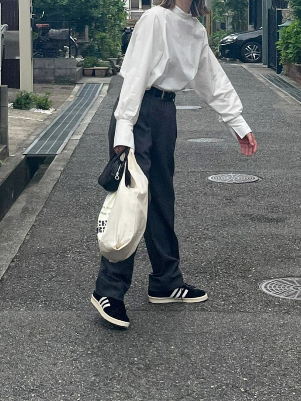 ホワイト系のシャツ/ブラウス、グレー系のスラックス、ブラック系のスニーカーを着用したレディースの春コーディネートの3枚目の写真