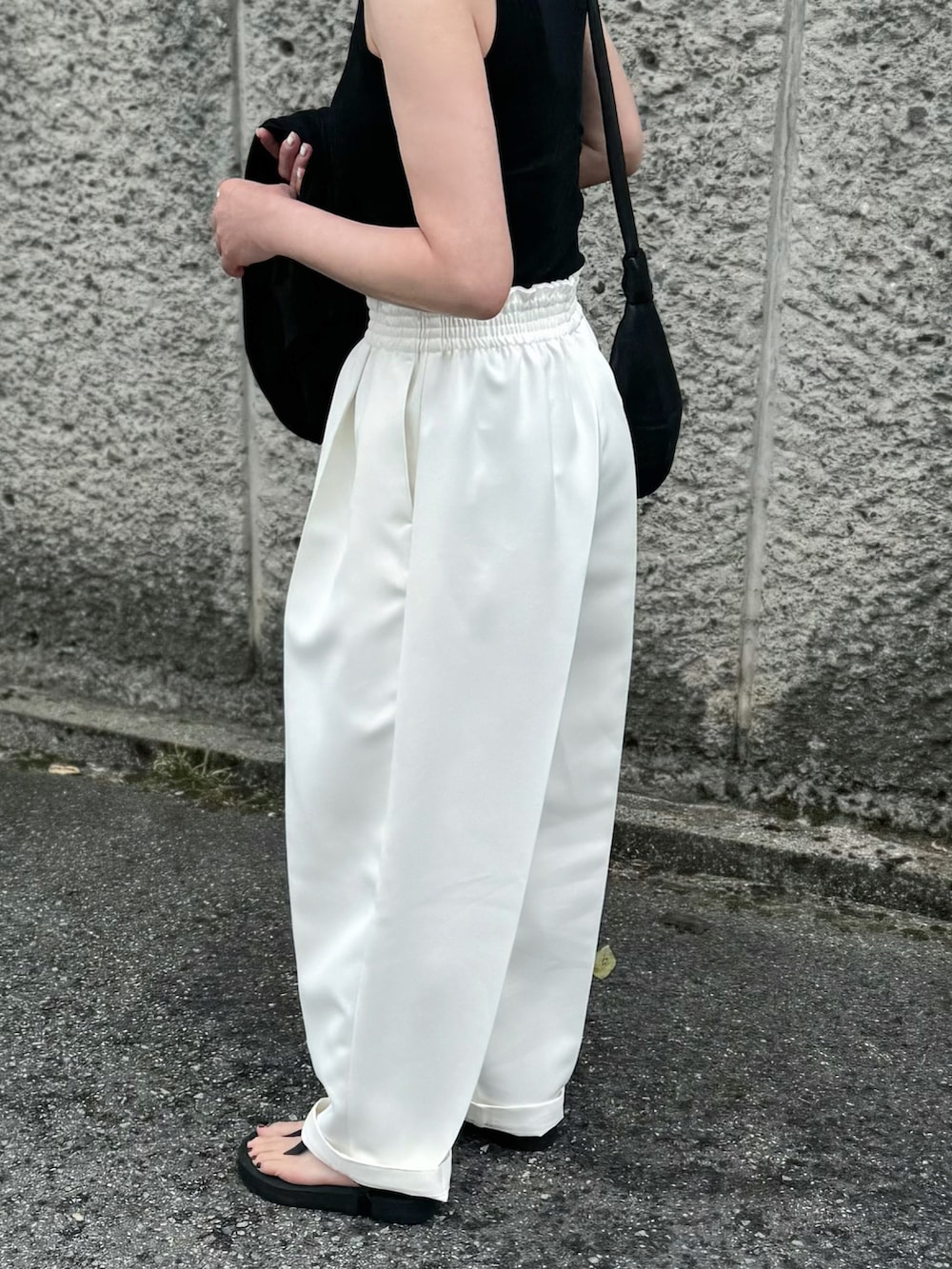 ブラック系のTシャツ/カットソー、ホワイト系のパンツ、ブラック系のサンダルを着用したレディースの春コーディネートの3枚目の写真