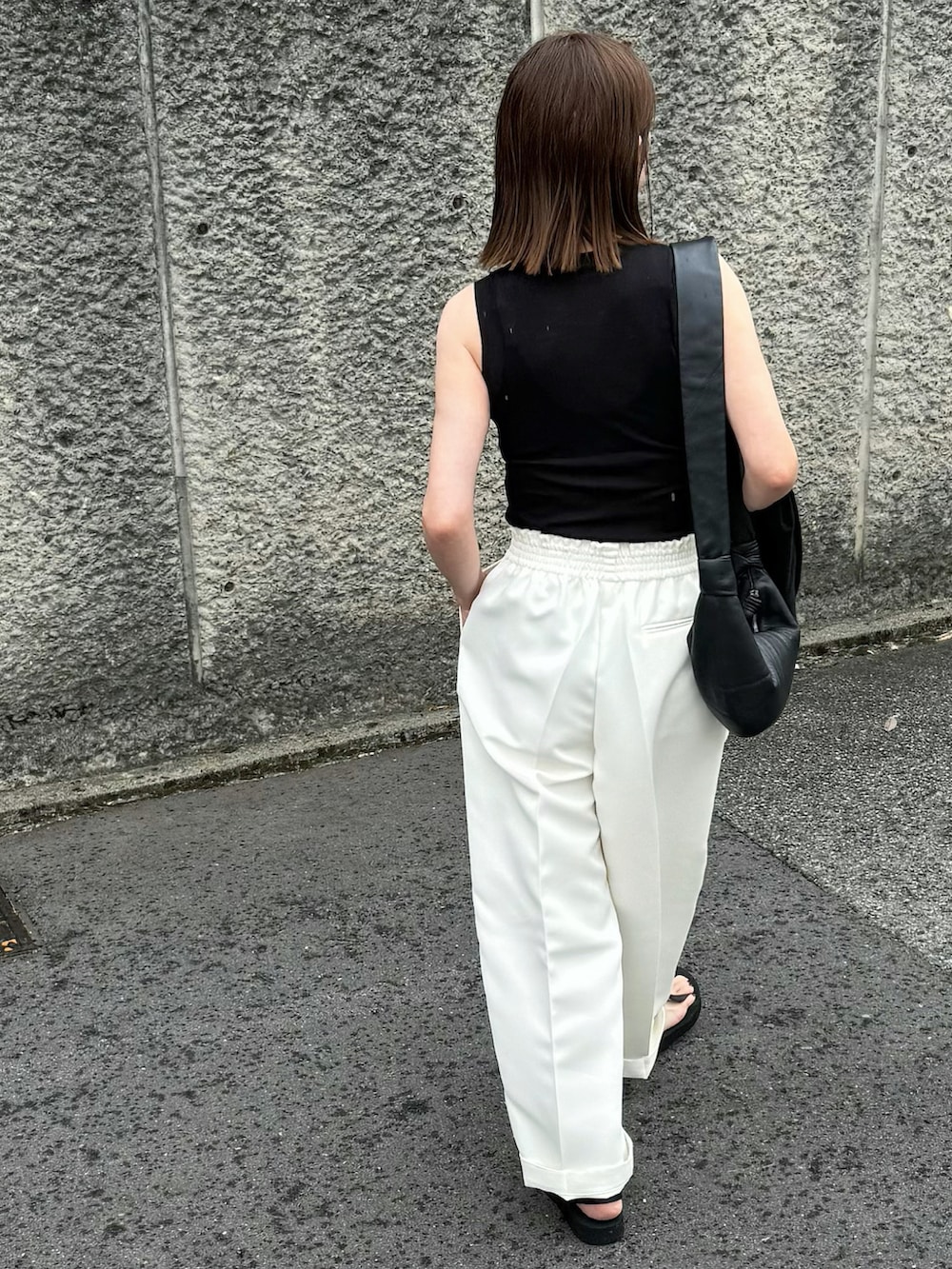 ブラック系のTシャツ/カットソー、ホワイト系のパンツ、ブラック系のサンダルを着用したレディースの春コーディネートの2枚目の写真