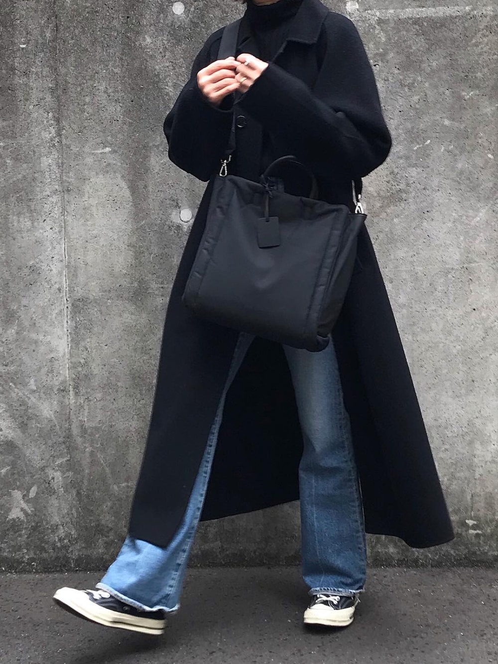 ブラック系のショルダーバッグ、ブルー系のデニムパンツ、ブラック系のスニーカーを着用したレディースの冬コーディネートの4枚目の写真