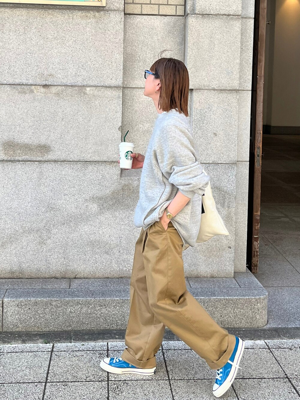 グレー系のスウェット、ベージュ系のチノパンツ、ブラウン系のトートバッグを着用したレディースの秋コーディネートの4枚目の写真