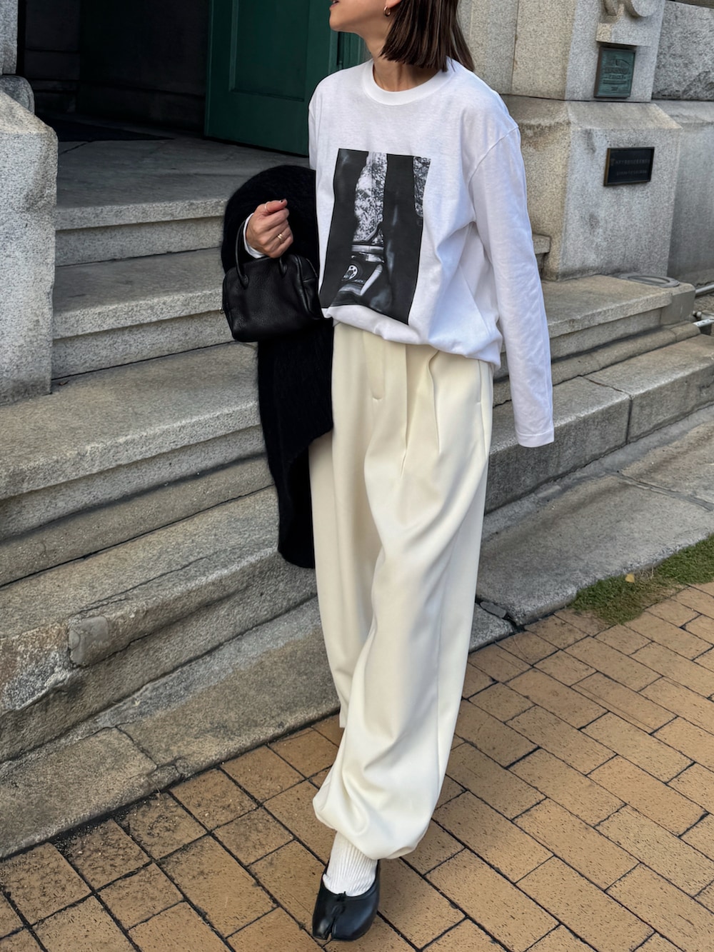 ブラック系のパンツ、ブラック系のバレエシューズ、ゴールド系のピアス（両耳用）を着用したレディースの秋コーディネートの3枚目の写真