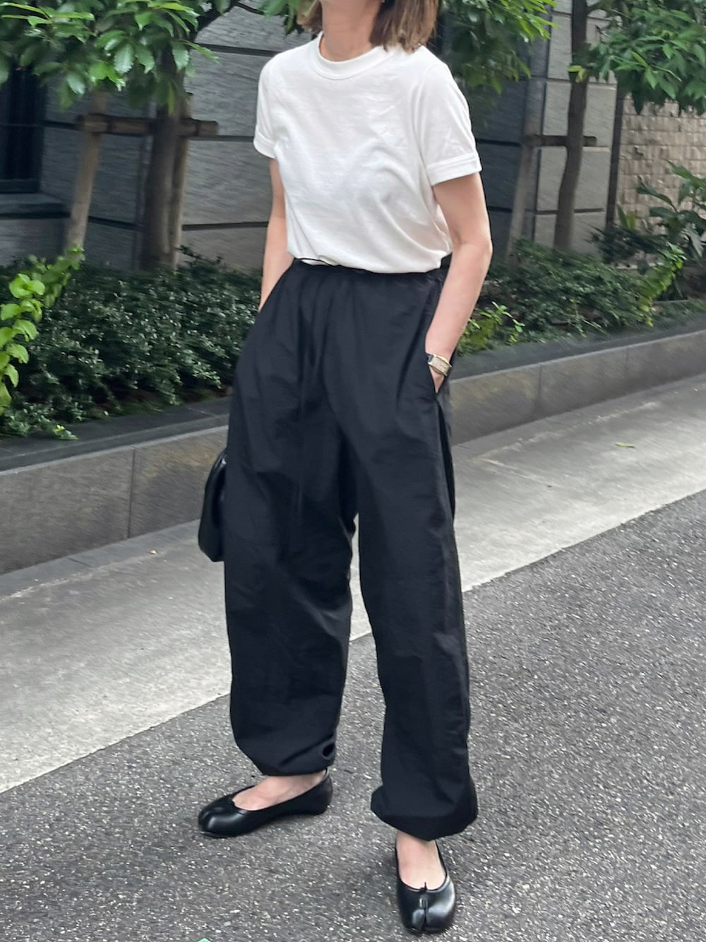 ホワイト系のTシャツ/カットソー、ブラック系のパンツ、ブラック系のバレエシューズを着用したレディースの夏コーディネートの3枚目の写真