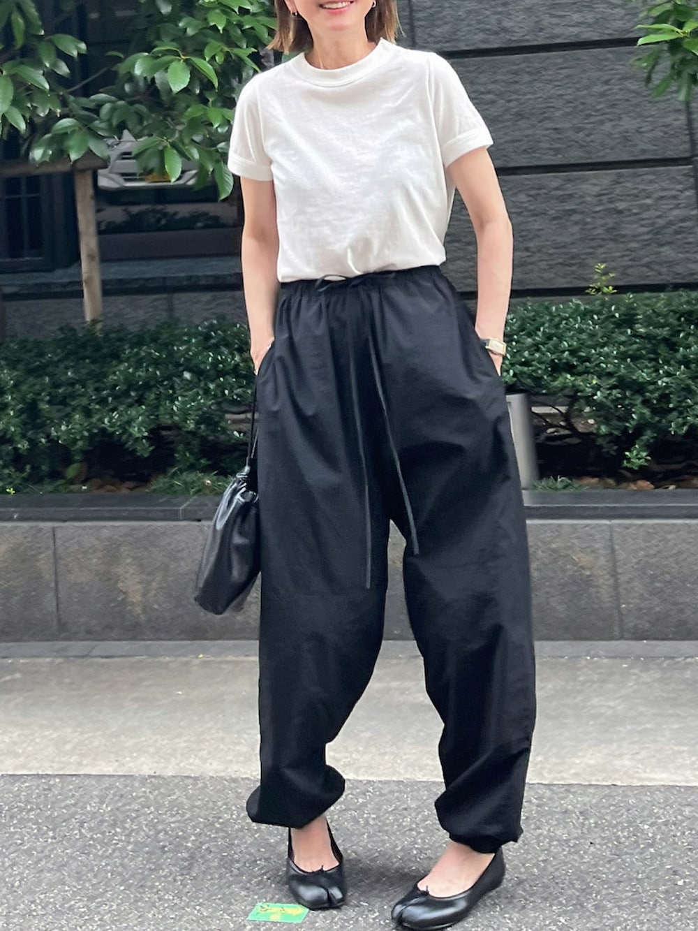 ホワイト系のTシャツ/カットソー、ブラック系のパンツ、ブラック系のバレエシューズを着用したレディースの夏コーディネートの2枚目の写真