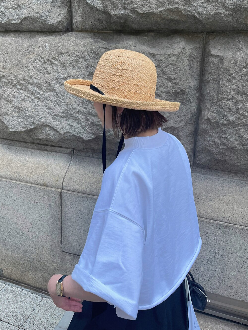 ホワイト系のTシャツ/カットソー、ブラック系のハット、シルバー系のブレスレットを着用したレディースの夏コーディネートの2枚目の写真