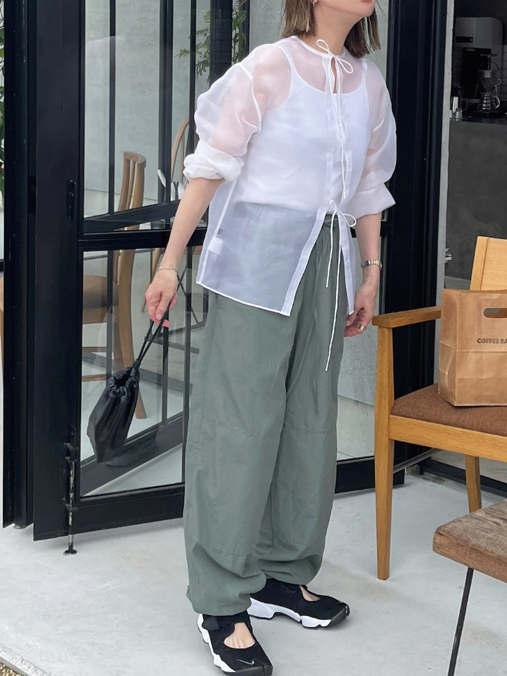 ホワイト系のシャツ/ブラウス、ブラック系のスニーカーを着用したレディースの夏コーディネートの2枚目の写真