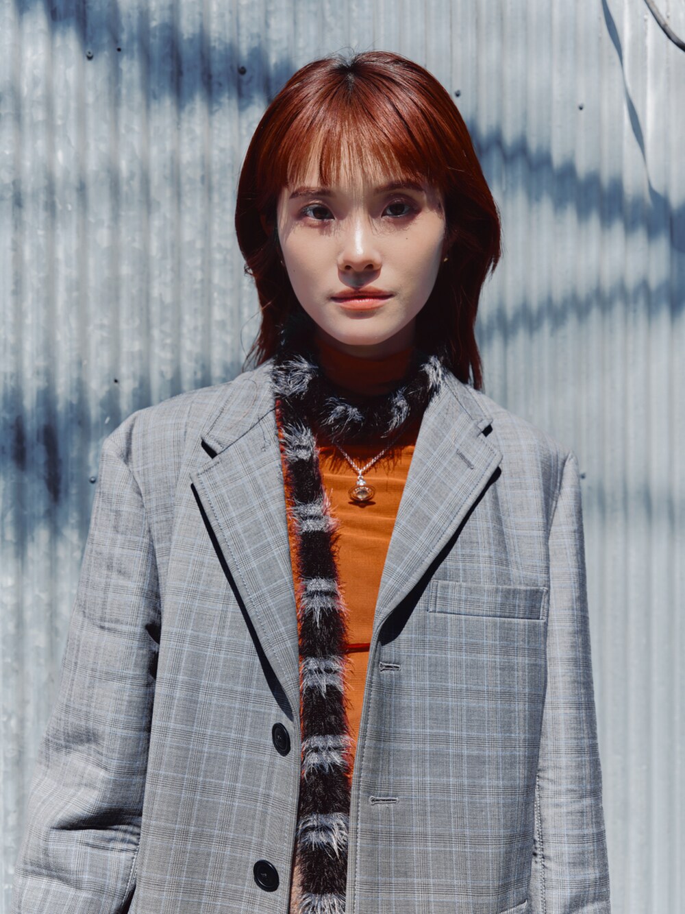 オレンジ系のTシャツ/カットソー、グレー系のテーラードジャケット、ブラウン系のスカートを着用したレディースの春コーディネートの4枚目の写真