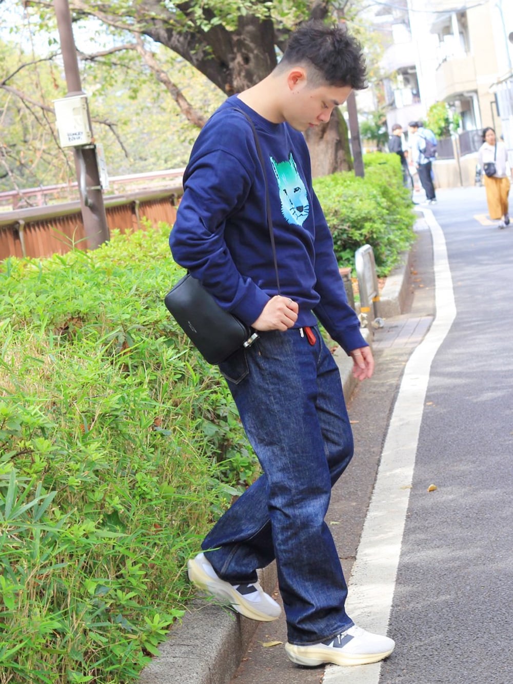 ブルー系のデニムパンツ、ブラック系のショルダーバッグ、ブルー系のスウェットを着用したメンズの秋コーディネートの3枚目の写真