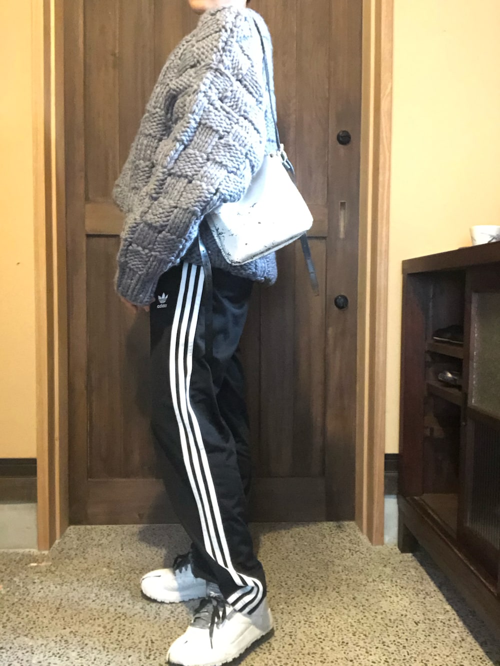 グレー系のニット/セーター、ブラック系のその他パンツ、ホワイト系のスニーカーを着用したレディースの冬コーディネートの2枚目の写真